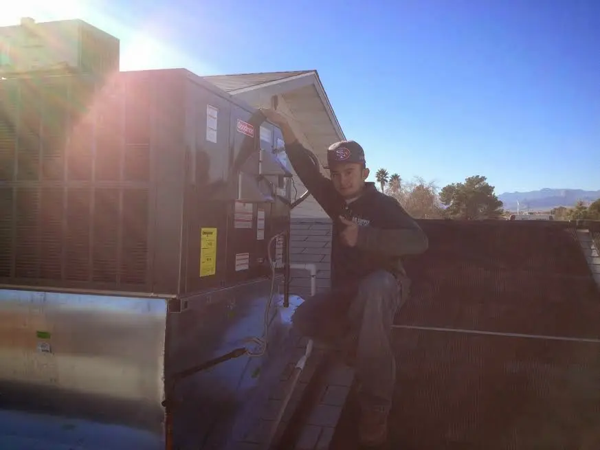 HVAC technician performing Boiler Repair on a rooftop unit in Kerman